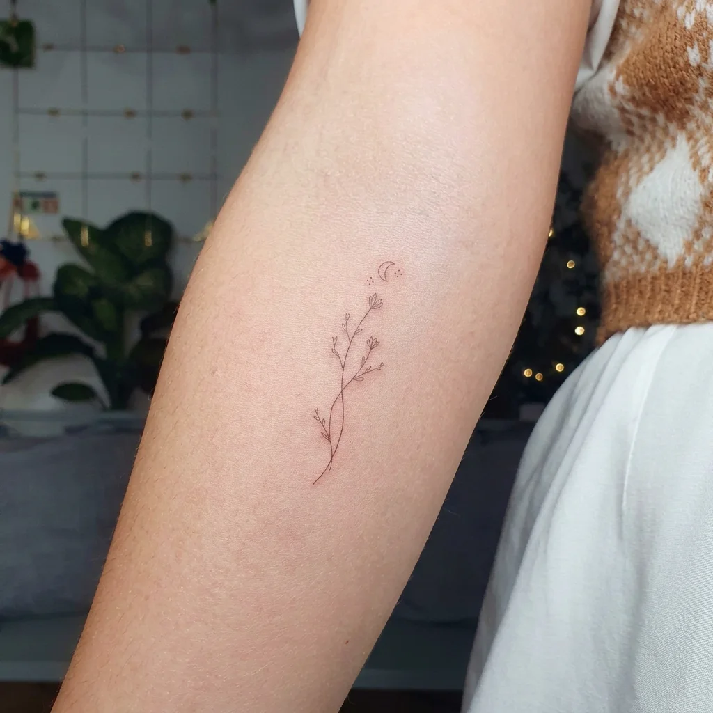Fine line tattoo of a crescent moon and small wildflower stem on the forearm